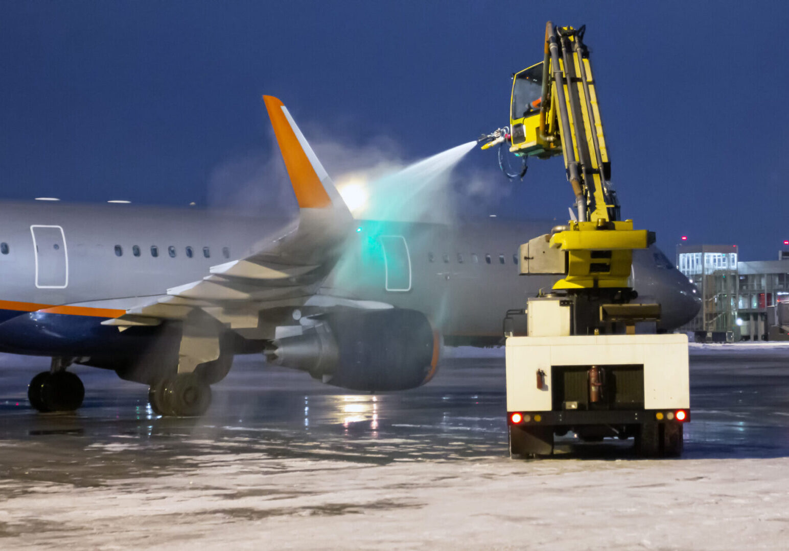 Airplane being de-iced on snowy tarmac.